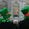 Two people watching a St Patrick's Day parade.