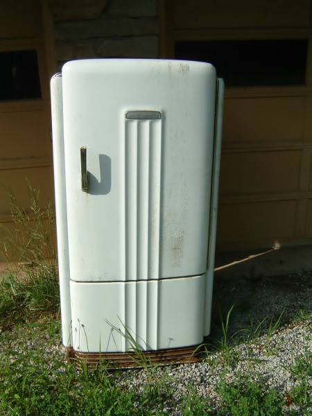 Old worn white metal refrigerator.