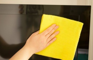 Cleaning a flat screen TV with a soft cloth.