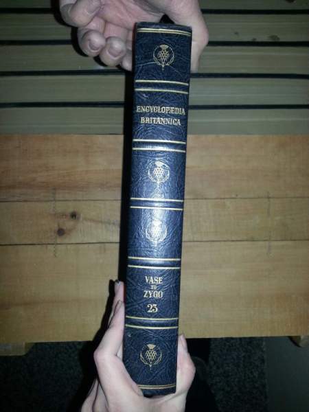 Someone holding up a volume to show the spine of the book.