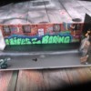 This handmade diorama is an urban street scene with telephone polls, brick walls with windows and graffiti.
