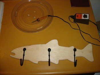 Full view of unpainted fish coat rack with wood burner..