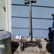 Old reel mower leaning up against a house wall.