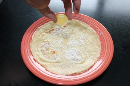 Making Crepes - Squeezing lemon onto sugared crepe.