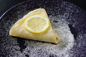 Making Crepes - Triangular folded crepe sprinkled with sugar and topped with a lemon slice.