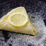 Making Crepes - Triangular folded crepe sprinkled with sugar and topped with a lemon slice.