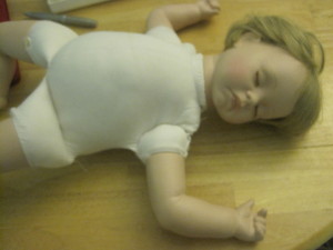 Baby doll lying on its back asleep.