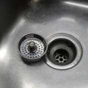 Drain strainer sittling next to drain in clean sink.