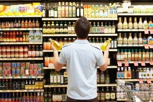 A man looking at a rack of different types of oil at a supermarket.