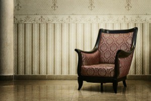 An antique chair in a room with expensive looking wallpaper.