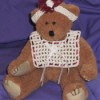 Teddy bear wearing bib and headband.