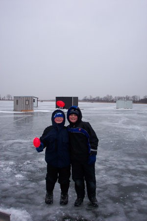 Two people dressed for winter standing on ice covered water.