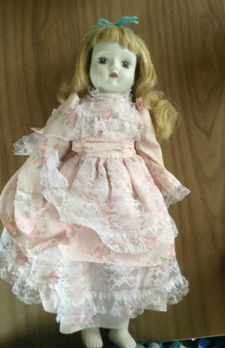 Blond haired porcelain doll with lacy pink dress.