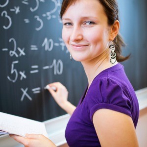 A math teach writing on a chalk board.