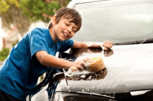 Young teen boy washing the car.