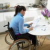 A woman sitting at table in a wheelchair.