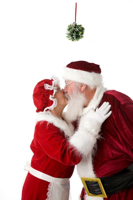 Santa and Mrs. Claus kissing under a kissing ball.