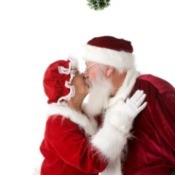 Santa and Mrs. Claus kissing under a kissing ball.