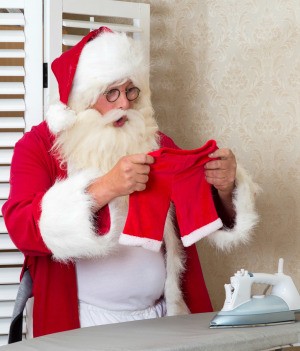 Santa looking at his pants that have been shrunk in the laundry.