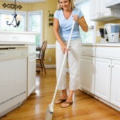A woman sweeping a nice wood kitchen floor.