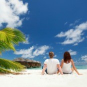 A couple sitting on the beach enjoying their honeymoon.