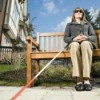 A blind woman sitting on a bench.