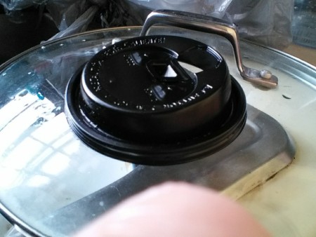 A disposable coffee lid being used as a pot scrubber