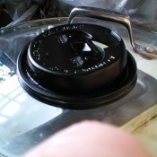 A disposable coffee lid being used as a pot scrubber