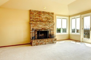 A carpetted living room with a fire place.