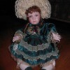 Brinn Porcelain Doll. Doll in green dress with ecru lace and lacy ruffled hat.