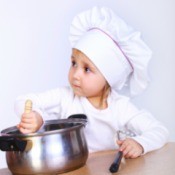 A toddler stirring food in a pot.
