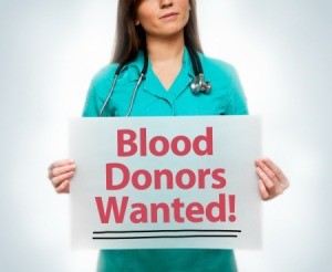 young medical professional holding sign- Blood Donors Wanted