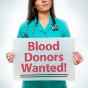 young medical professional holding sign- Blood Donors Wanted