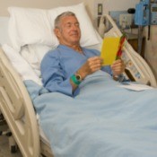 man in hospital bed reading a get well card