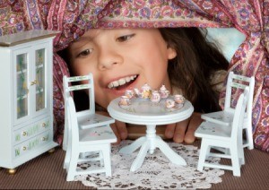 girl looking into doll house set for tea party