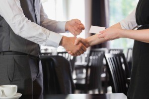 two people shaking hands and exchanging business cards