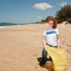 young beach cleanup volunteer on beach with yellow trash bag
