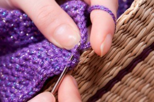 woman crocheting with purple yarn