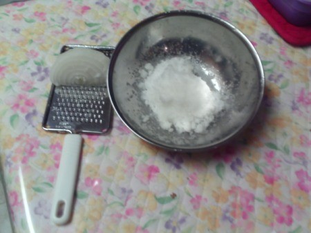 A grater with a part of a grated onion.