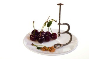 cherry pitter on plate with cherries and pits