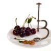 cherry pitter on plate with cherries and pits