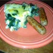 A plate with a green potato frittata and two sausages.