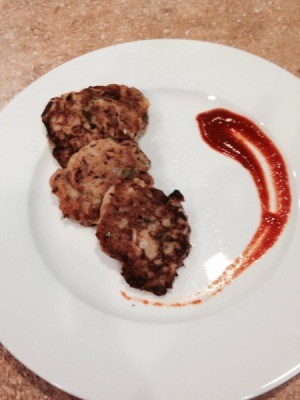 three croquettes on white plate with hot sauce on the side