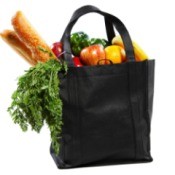 black shopping bag filled with fruit, veggies, and loaves of bread