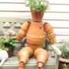 Terra cotta flowerpot man sitting on garden bench