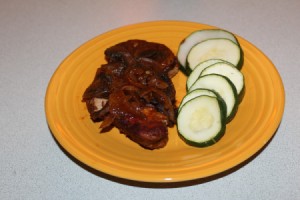 A plate of Italian pork chops and veggies.