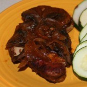 A plate of Italian pork chops and veggies.