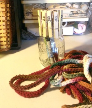 glass jar with clothes pins behind crochet chain