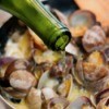 pouring white wine over simmering clams