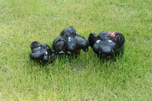 three cute black plaster elephants in the grass